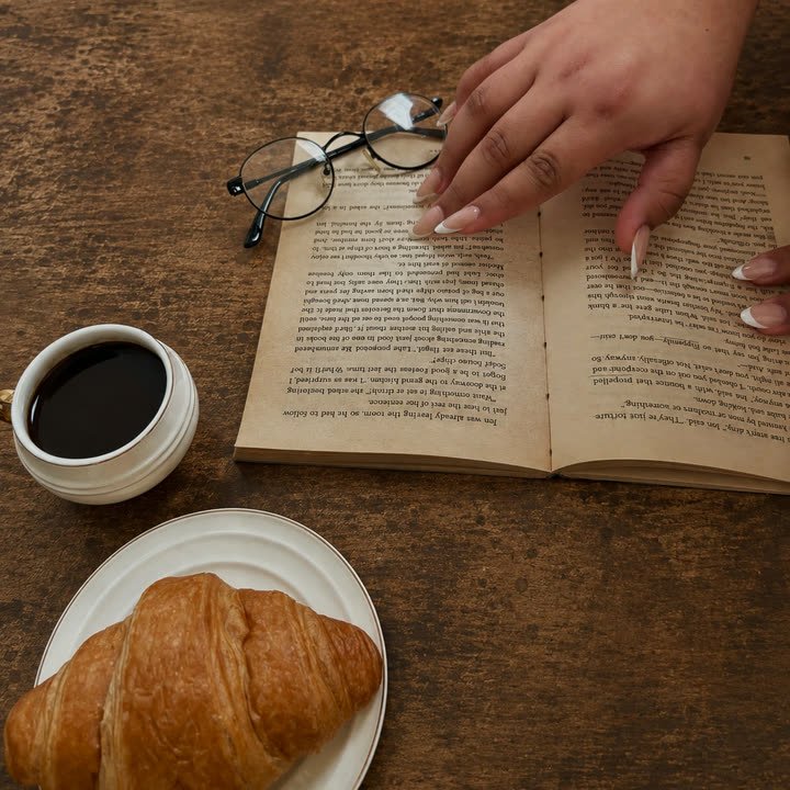 White Tip press-on nails, nude almond with clean white French tips, on an open book beside a coffee